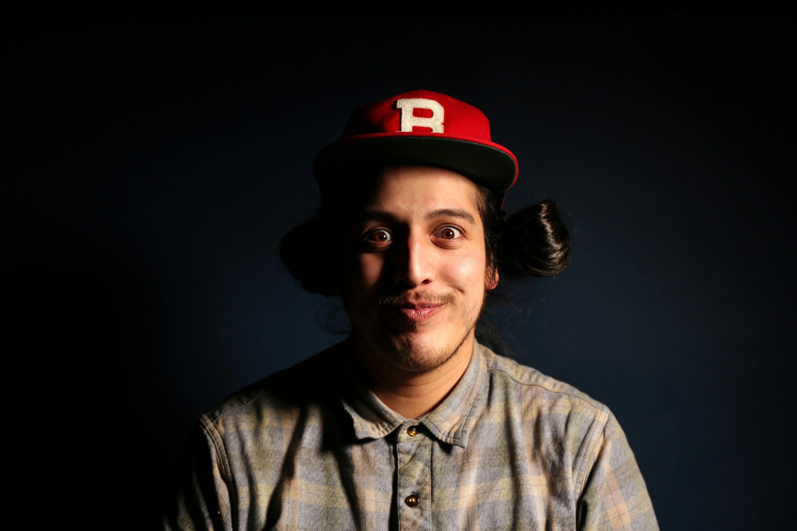 Humorous studio portrait of a man in a red cap with a quirky expression, showcasing playful fashion.